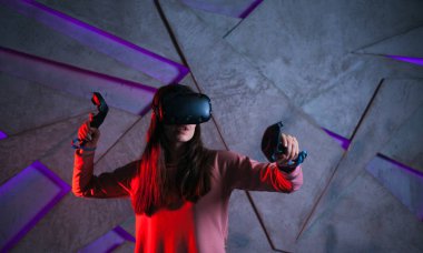 Kılıç kullan. Sanal kasklı genç bir kadın, sanal kılıçların kolları gibi her iki elinde de kontrolörler kullanır..