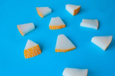 Kavun mavi bir arka plan üzerinde küçük parçalar halinde kesilmiş, aperatifler için taze meyve,