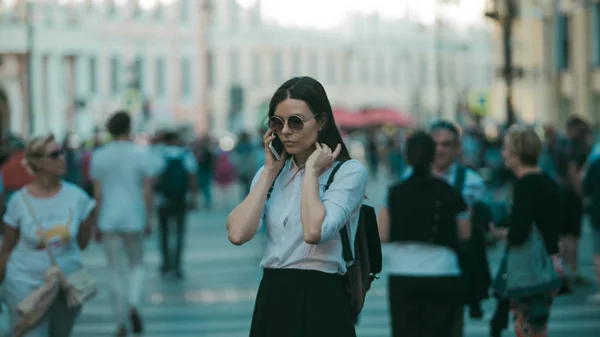 La chica en la multitud en las calles de la gran ciudad. Una joven de la ciudad usa un teléfono móvil —  Fotos de Stock