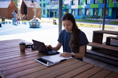 Esmer kız bir dizüstü bilgisayar önünde masa oturan, gülümseyerek, monitör ve kağıt bakarak. Çevrimiçi iletişim kurar.