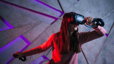 Kılıç kullan. Sanal kasklı genç bir kadın, sanal kılıçların kolları gibi her iki elinde de kontrolörler kullanır..
