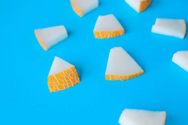 Kavun mavi bir arka plan üzerinde küçük parçalar halinde kesilmiş, aperatifler için taze meyve,