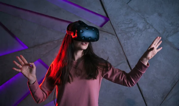 Watch out. Young woman with vr glasses and fluttering hair actively reacts, is afraid of what is happening in the game.