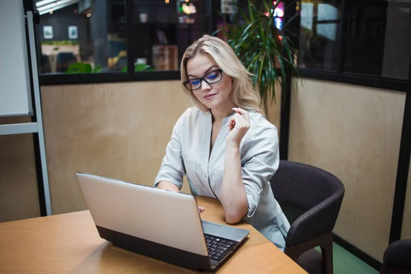 Jovem mulher confiante trabalhando em um laptop no escritório . — Fotografia de Stock