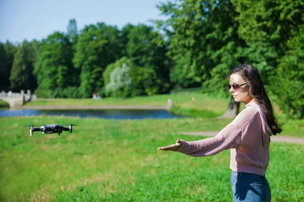 Camina con un dron. Mujer joven con gafas negras lanza un dron de vuelo bajo. Llega a los aviones no tripulados de vuelo bajo, capturas . —  Fotos de Stock