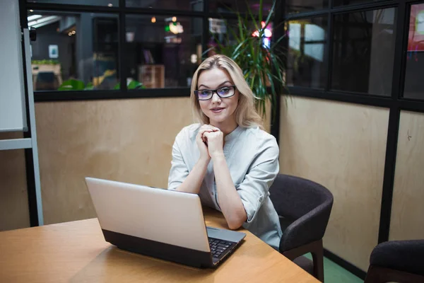 Работник офиса или студент работает над ноутбуком. Счастливая уверенная блондинка в стильном офисе . — стоковое фото