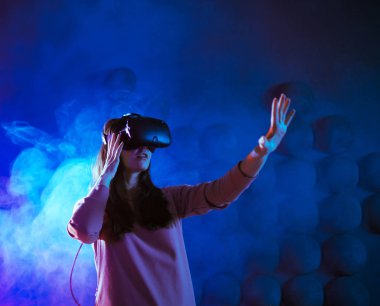 Yolculuk başlıyor. VR deneyimi sırasında neon ve duman fütüristik arka plana karşı havaya dokunan genç kadın hayret verici..