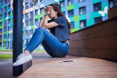 Ön planda yatan bir akıllı telefon, bulanık arka plan, kız, ağlıyor, ahşap bir tezgah üzerinde otururken yüz kapsayan.