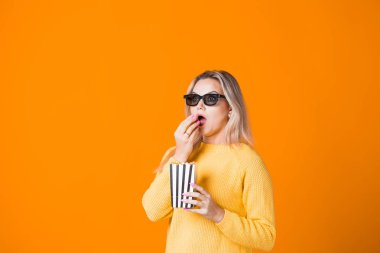 Üç boyutlu gözlüklü, film izleyen ve patlamış mısır yiyen genç ve neşeli bir kadın..