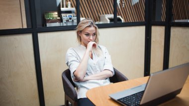 Dizüstü bilgisayarın başında çok çalışan genç bir kadın.