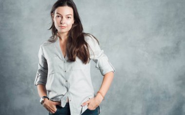 Günlük giysiler içinde, kendine güvenen esmer bir kadın. Gülümseyen ve sakin kız