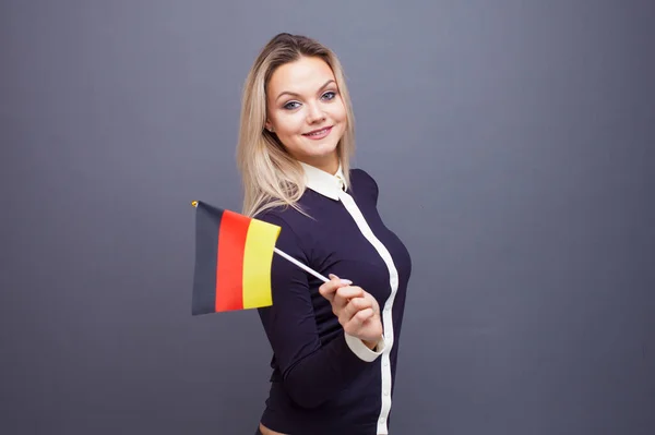 Einwanderung und Fremdsprachenstudium, Konzept. Eine junge lächelnde Frau mit einer Deutschland-Fahne in der Hand. — Stockfoto