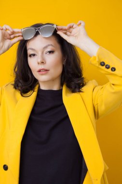 Parlak sarı ceketli ve aynalı güneş gözlüklü şık ve cesur bir esmer..