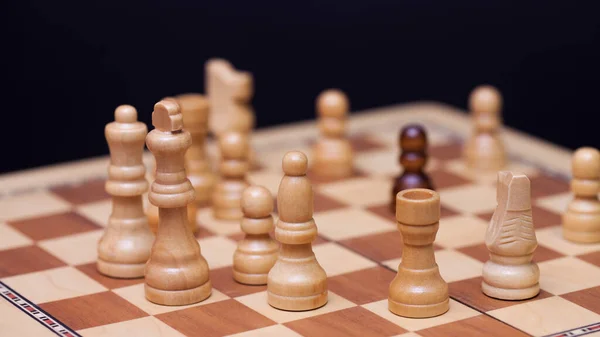 Шахи, багато шахових фігур на дошці. Білі фігури оточили чорного пішака.. — стокове фото