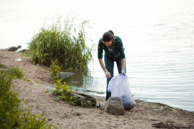 Çöpleri temizlemek, gönüllü iş. Doğayı önemsemek. İnsanlar plaja bir sürü plastik çöp bırakmışlar.
