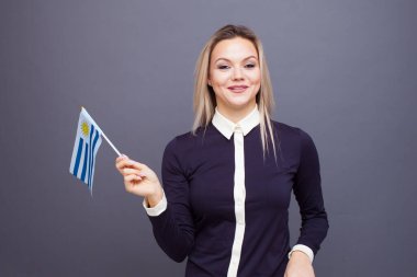 Göçmenlik ve yabancı dil eğitimi, konsept. Elinde Uruguay bayrağı olan gülümseyen genç bir kadın..