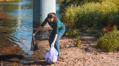 Çöpleri temizlemek, gönüllü iş. Doğayı önemsemek. İnsanlar plaja bir sürü plastik çöp bırakmışlar.