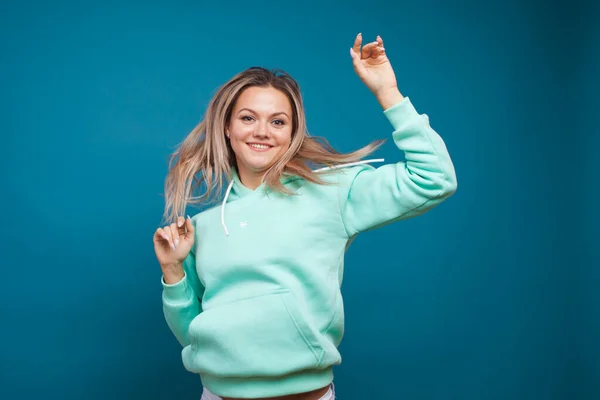 Šťastná dívka s úsměvem, portrét v ateliéru na modrém pozadí. Pozitivní mladá blondýna žena — Stock fotografie