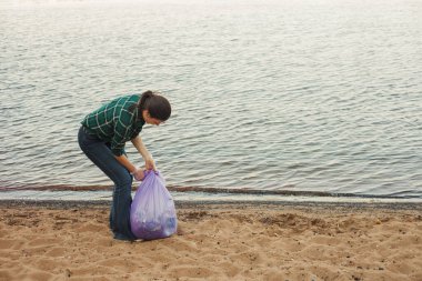 Çöpleri temizlemek, gönüllü iş. Doğayı önemsemek. İnsanlar plaja bir sürü plastik çöp bırakmışlar.