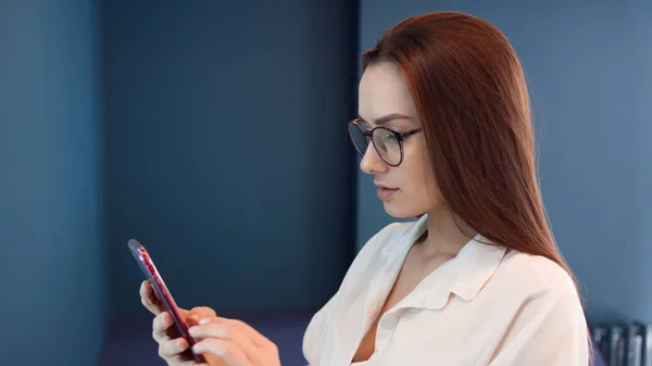 Mujer joven de negocios con estilo utiliza un teléfono inteligente para comunicarse en mensajeros. — Foto de Stock