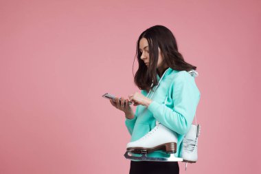 Artistik patinaj, hobiler ve sağlıklı aktif bir yaşam tarzı. Omzunda patenlerle parlak kapüşonlu neşeli bir kız.