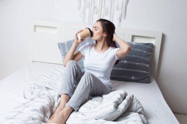 Sabah yataktan kalk ve kahveni iç. Genç güzel kız yatakta oturuyor.