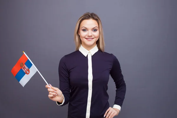 Einwanderung und Fremdsprachenstudium, Konzept. Eine junge lächelnde Frau mit einer Serbien-Fahne in der Hand. — Stockfoto