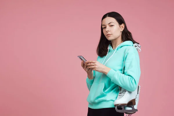 Figure skating, Hobbies and a healthy active lifestyle. A cheerful girl in a bright hoodie with skates on her shoulder — Stock Photo, Image