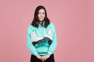 Parlak kapüşonlu komik kız paten sahasına gitmeye hazırlanıyor. Omzunda patenlerle patenci.