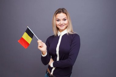 Göçmenlik ve yabancı dil eğitimi, konsept. Elinde Belçika bayrağı olan gülümseyen genç bir kadın..