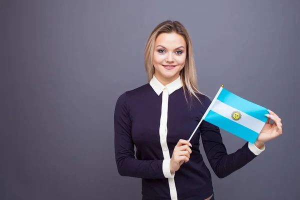 Inmigración y el estudio de lenguas extranjeras, concepto. Una joven sonriente con una bandera argentina en la mano. —  Fotos de Stock