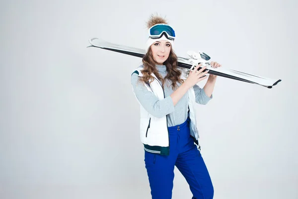 Skieuse souriante sur fond blanc, portrait en studio. Une jeune femme en vêtements d'hiver et équipement de ski — Photo