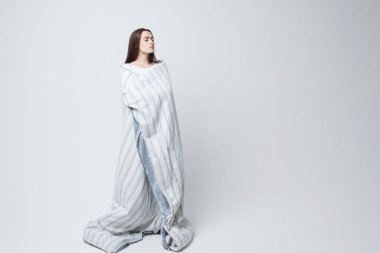 Sağlıklı bir uyku ve uykusuzluk, battaniyeye sarılmış güzel genç bir kadın.