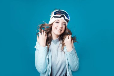 Şapkalı ve kar maskeli neşeli genç bir kadın. Kışlık ceketli bir kız.