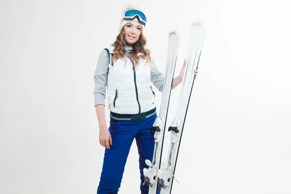 Chica esquiadora sonriente sobre un fondo blanco, retrato en el estudio. Una joven con ropa de invierno y equipo de esquí — Foto de Stock