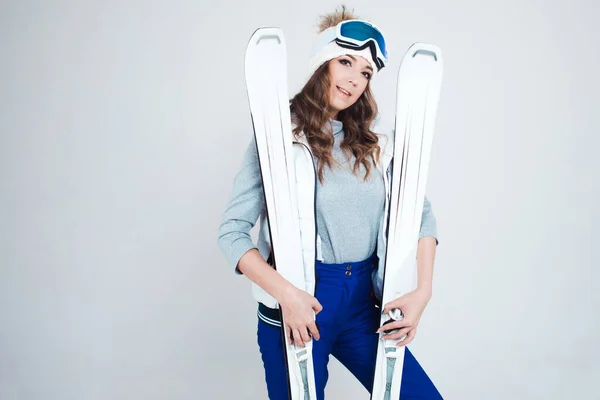 Skieuse souriante dans un chapeau et un masque pour skier. Une jeune femme vêtue pour le ski et les activités de plein air. — Photo