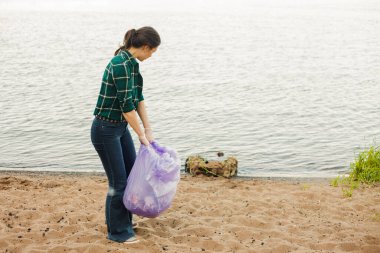 Çöpleri temizlemek, gönüllü iş. Doğayı önemsemek. İnsanlar plaja bir sürü plastik çöp bırakmışlar.