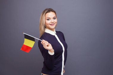 Göçmenlik ve yabancı dil eğitimi, konsept. Elinde Belçika bayrağı olan gülümseyen genç bir kadın..