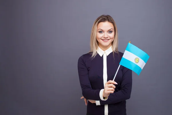 Inmigración y el estudio de lenguas extranjeras, concepto. Una joven sonriente con una bandera argentina en la mano. —  Fotos de Stock