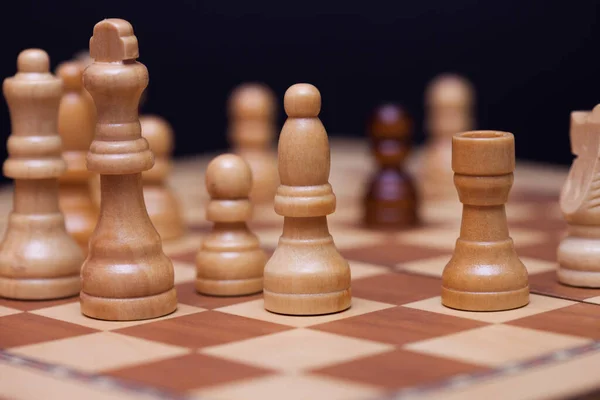 Шахи, багато шахових фігур на дошці. Білі фігури оточили чорного пішака.. — стокове фото