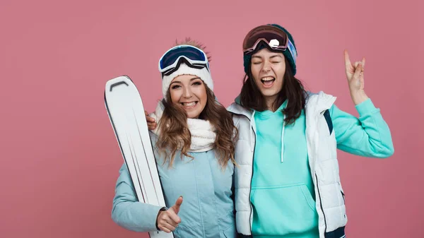 Двоє смішних друзів в зимовому одязі на рожевому тлі. Два лижника — стокове фото