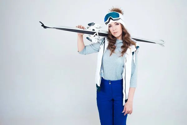 Skieuse souriante sur fond blanc, portrait en studio. Une jeune femme en vêtements d'hiver et équipement de ski — Photo