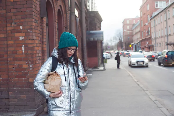 Kurier oder freiwilliger Helfer trägt Lebensmittel in einer Papiertüte. Eine junge Frau in einer warmen Jacke — Stockfoto