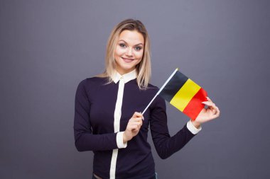 Göçmenlik ve yabancı dil eğitimi, konsept. Elinde Belçika bayrağı olan gülümseyen genç bir kadın..