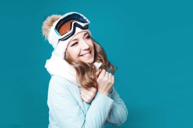 Şapkalı ve kar maskeli neşeli genç bir kadın. Kışlık elbiseli kız.