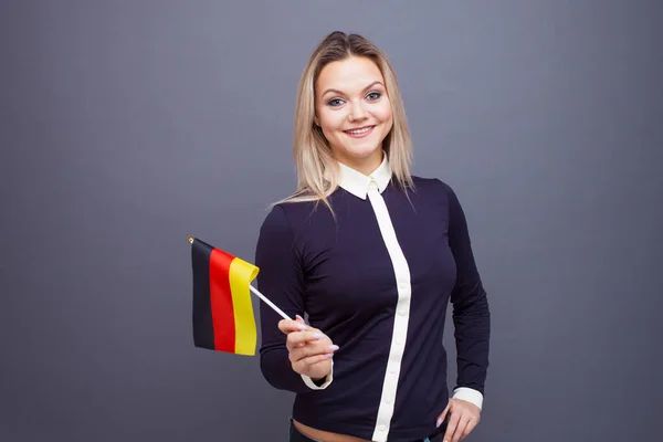 Invandring och studier av främmande språk, begrepp. En ung leende kvinna med en tysk flagga i handen. — Stockfoto