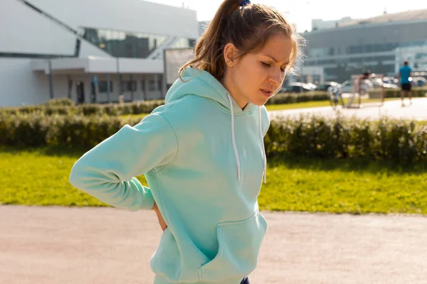 Sports injuries, a young female athlete kneads the lower back, sprains or muscles.