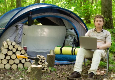 Bir laptop bir çadır kampında açık havada çalışan bir erkeğin.