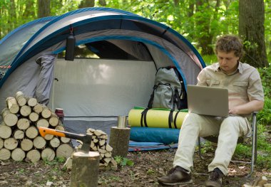 Bir laptop bir çadır kampında açık havada çalışan bir erkeğin.