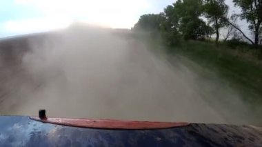 Otomobil araba lastikleri sürüş kırsal çakıl yolda yükselen toz. POV geri hareket görünümü.